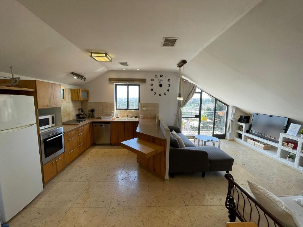 een keuken en een woonkamer met een bank en een koelkast bij Gorgeous Penthouse // Market Location // Panoramic in Jeruzalem