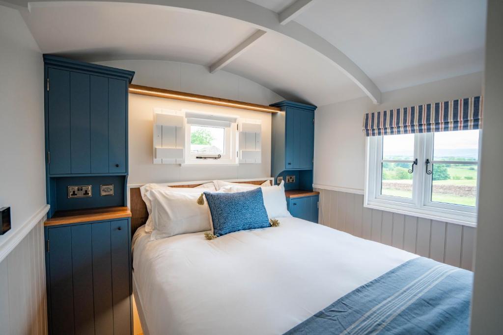 a bedroom with a bed with blue cabinets and a window at Inglewood Shepherd's Huts in Penrith