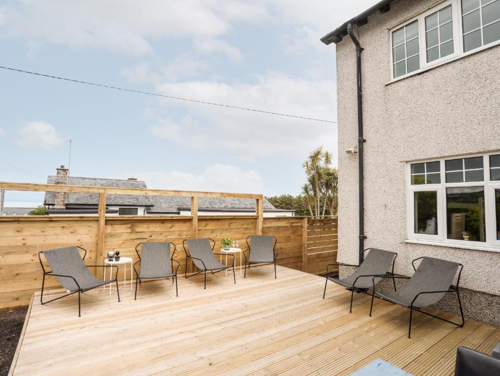 a patio with chairs and a table on a wooden deck at Hillcroft in Pwllheli