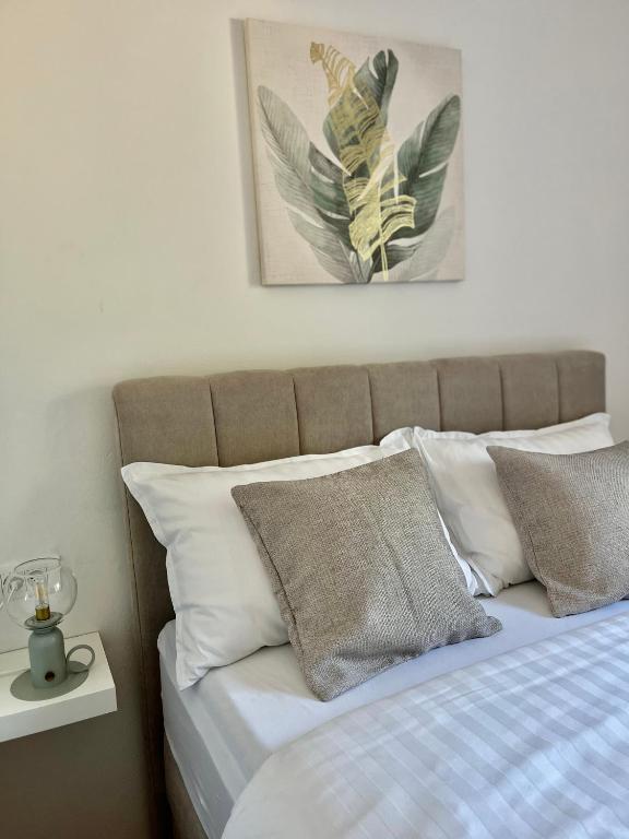 łóżko z białymi poduszkami i zdjęciem na ścianie w obiekcie Apartments Fortuna w Biogradzie na Moru