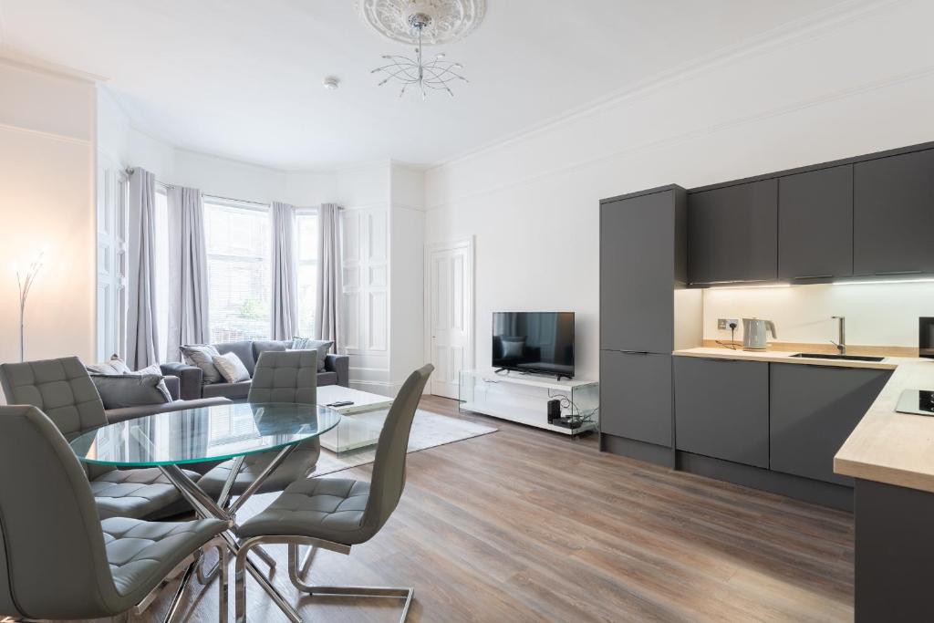 cocina y sala de estar con mesa de cristal y sillas en River View Apartment en Dundee