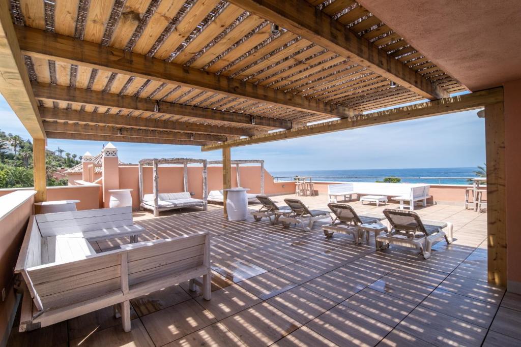 a patio with benches and tables and a view of the ocean at El Cortijo de Zahara by QHotels in Zahara de los Atunes