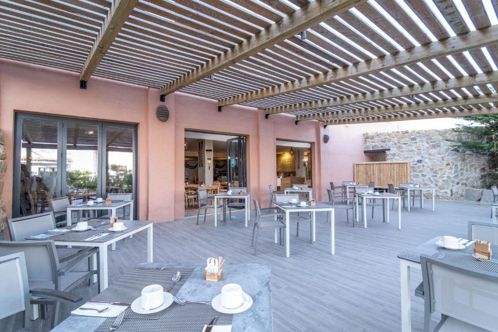 a restaurant with tables and chairs and a wooden ceiling at El Cortijo de Zahara by QHotels in Zahara de los Atunes