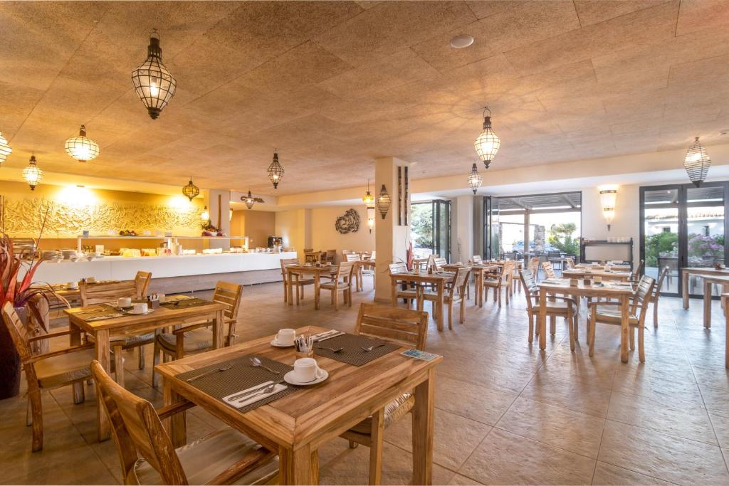 a restaurant with wooden tables and wooden chairs at El Cortijo de Zahara by QHotels in Zahara de los Atunes