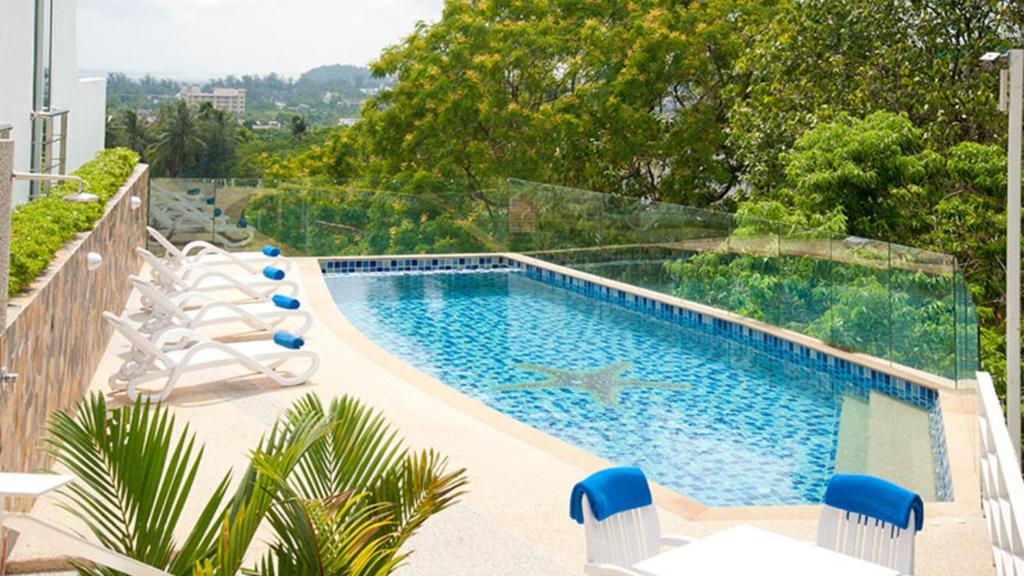 a swimming pool with lounge chairs next to at Kata Ocean View condominium by Lofty in Kata Beach