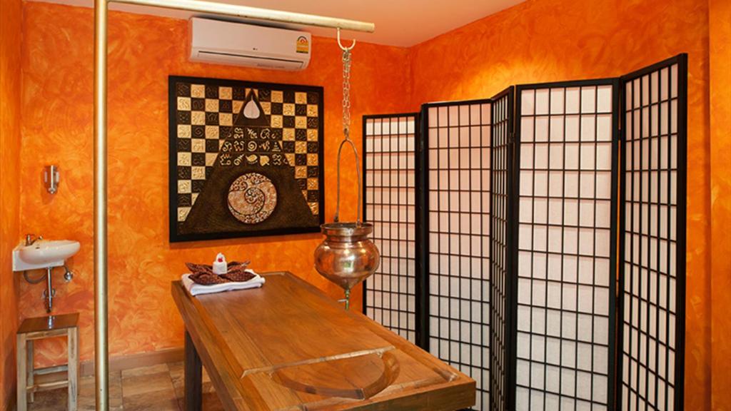a room with orange walls and a wooden table at Kata Ocean View condominium by Lofty in Kata Beach