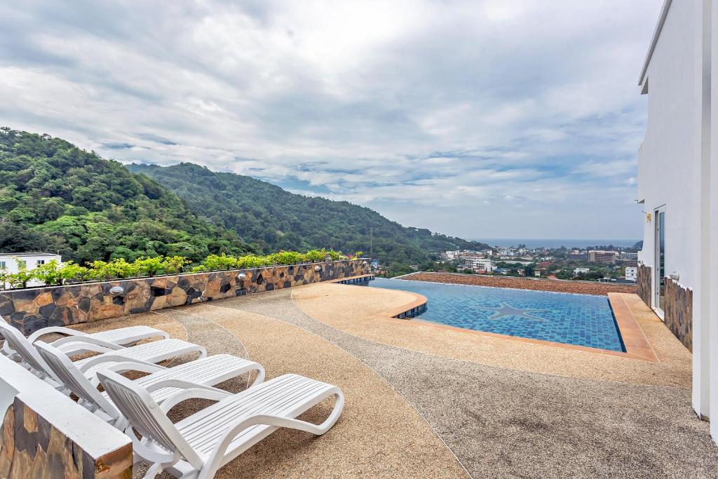 a group of white chairs sitting next to a swimming pool at Kata Ocean View condominium by Lofty in Kata Beach