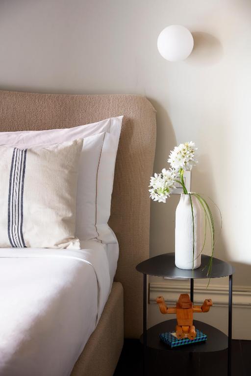 un letto con un tavolo e un vaso di fiori sopra di HOTEL VITE - By Naman Hotellerie a Roma