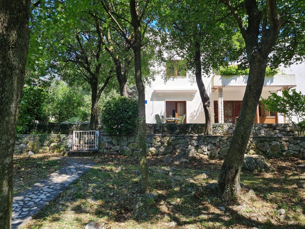 una casa con una pared de piedra y árboles en Apartment Morska oaza, en Klenovica