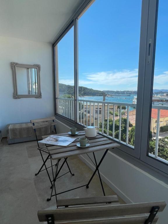 - une table et des chaises dans une pièce dotée de grandes fenêtres dans l'établissement Cosy T3 proche plage. Fibre. Clim, à Saint-Mandrier-sur-Mer