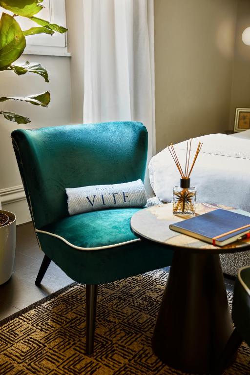 una camera con sedia verde, tavolo e letto di HOTEL VITE - By Naman Hotellerie a Roma