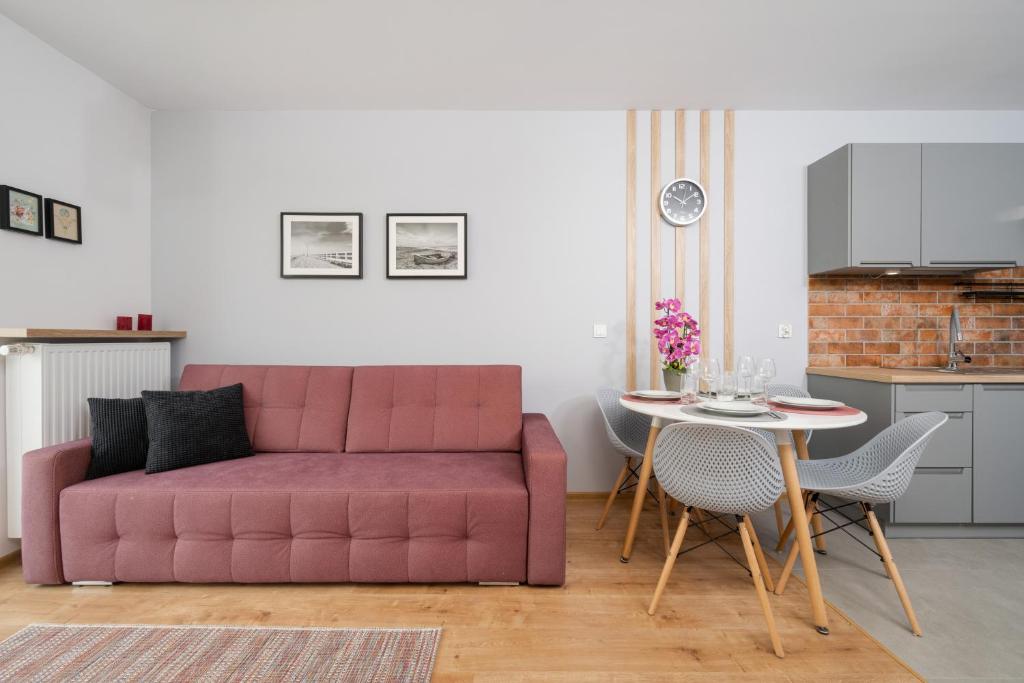 a living room with a red couch and a table at Apartment Kamienna Krzyki with FREE GARAGE Wrocław by Renters in Wrocław