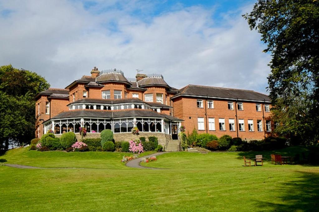 ein großes rotes Backsteingebäude mit einem großen Hof in der Unterkunft Macdonald Kilhey Court Hotel & Spa in Wigan