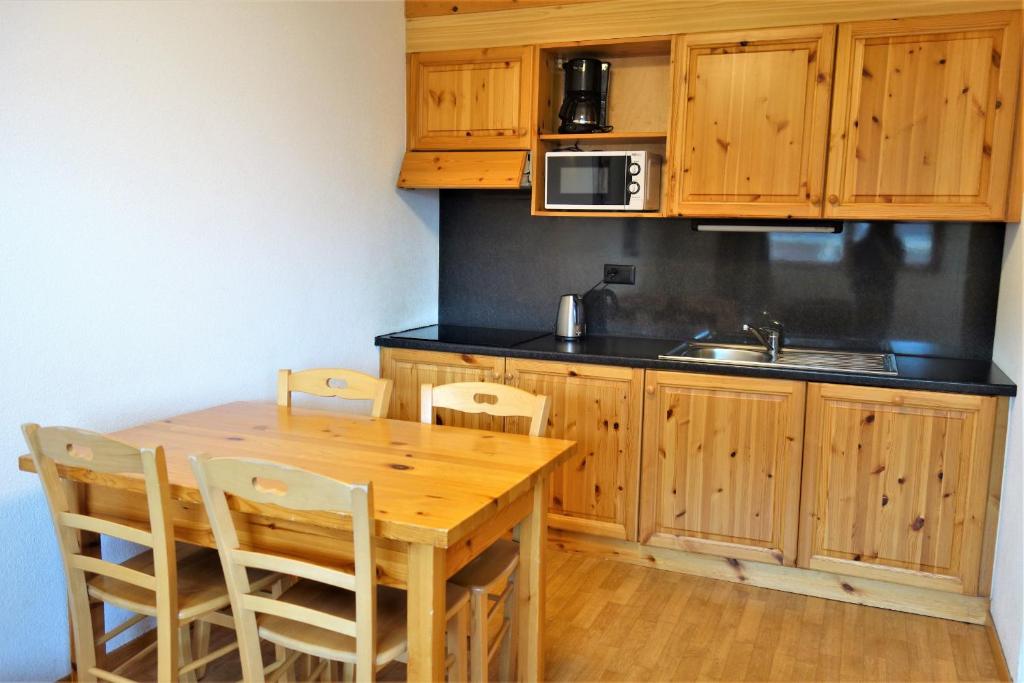 a kitchen with wooden cabinets and a wooden table and chairs at Pracondu 2 305 - OUTDOOR & FUN charming apartment in Nendaz