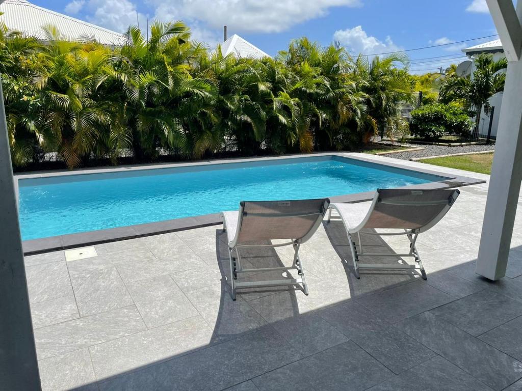 einen Tisch und zwei Stühle neben einem Pool in der Unterkunft Gîtes de Corneille, Bungalow Sweet Mango in Le Moule