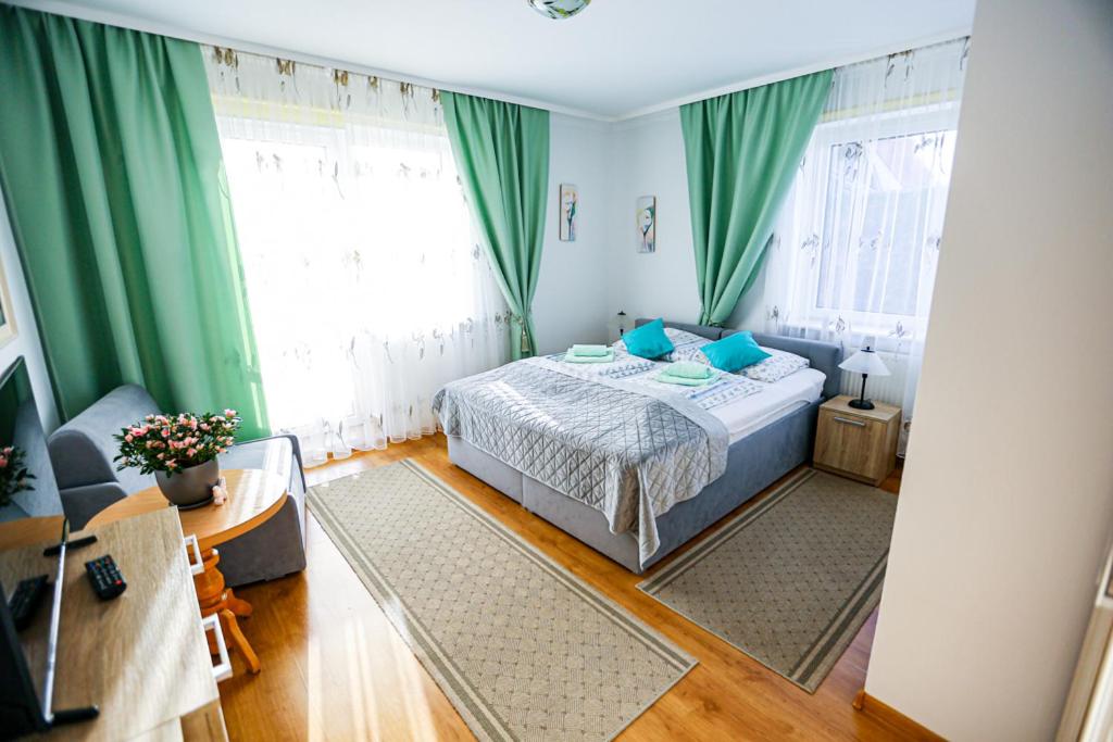 a bedroom with a bed with blue pillows and green curtains at Villa Nadmorska Łeba Centrum in Łeba