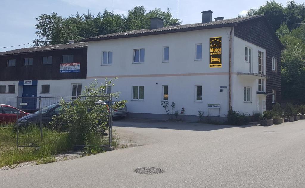 un edificio blanco con un cartel en el costado en JOHN’S MOTEL APPARTEMENTHAUS, en Attnang-Puchheim