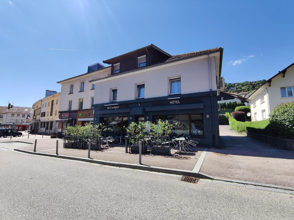 um edifício com mesas e cadeiras em frente a uma rua em Hôtel Influences La Bresse em La Bresse