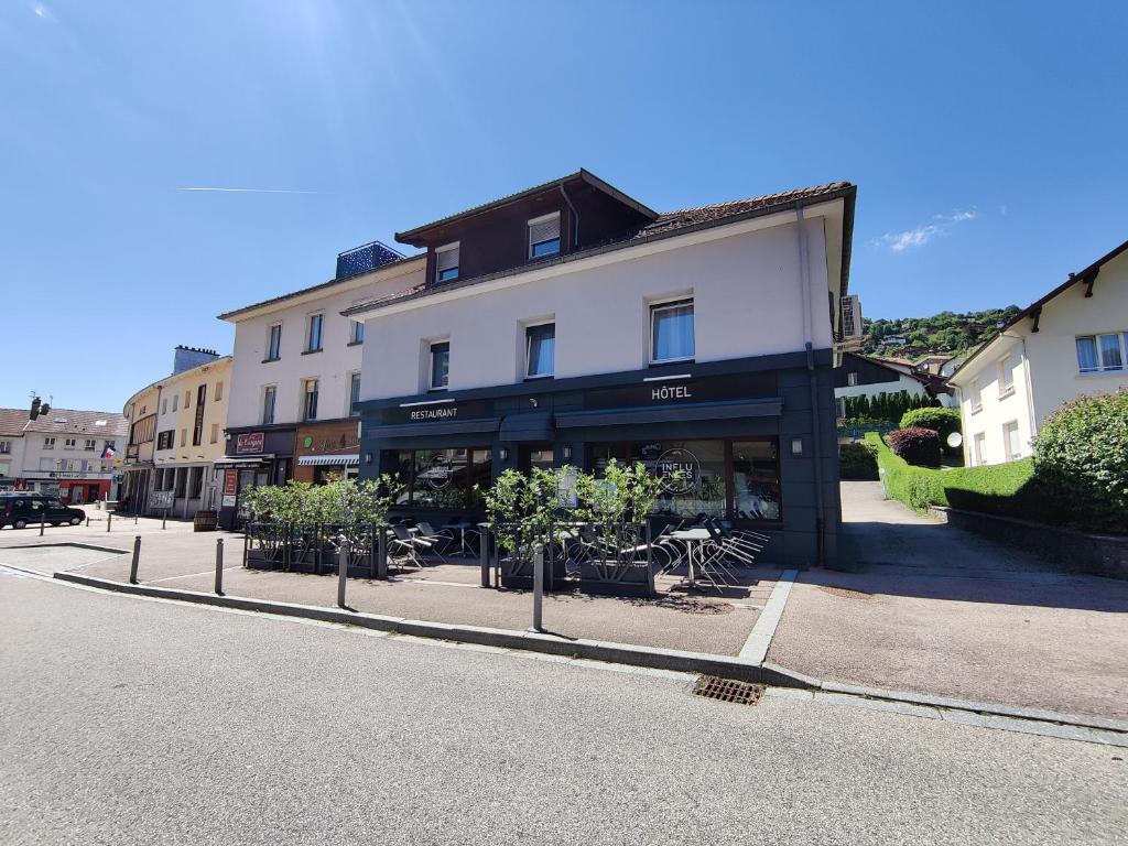 a building with tables and chairs in front of a street at Hôtel Influences La Bresse in La Bresse