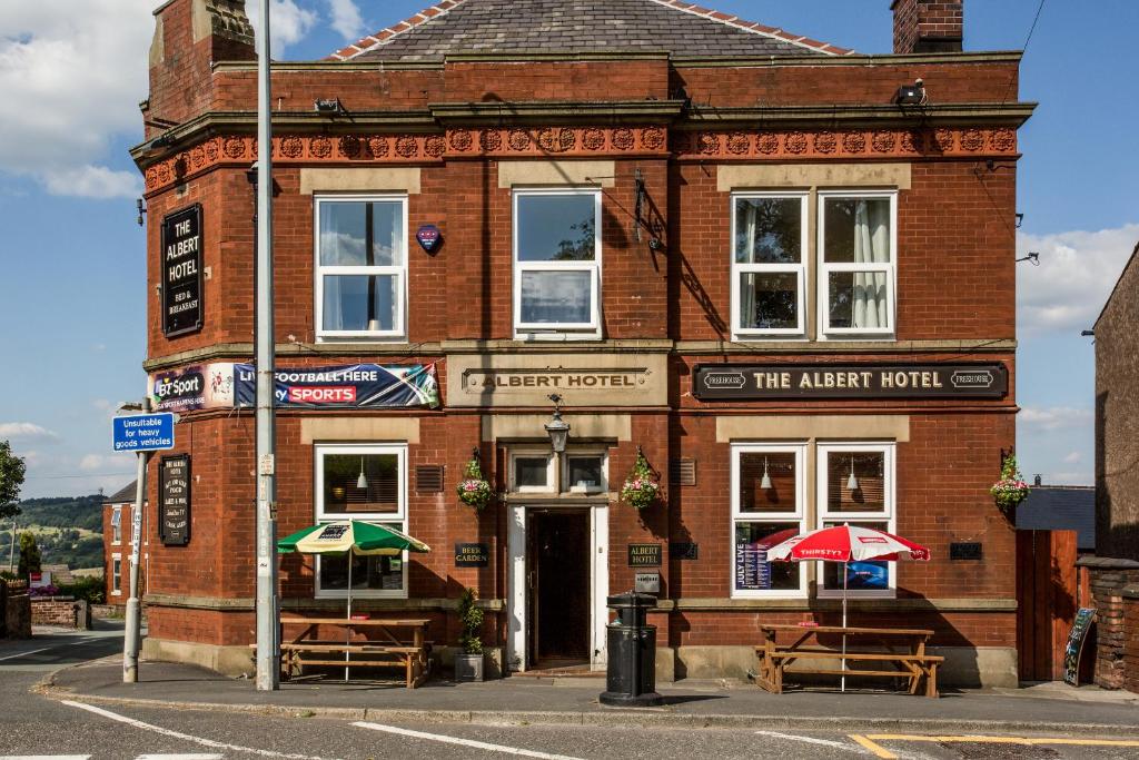 a brick building with two umbrellas in front of it at The Albert in Disley