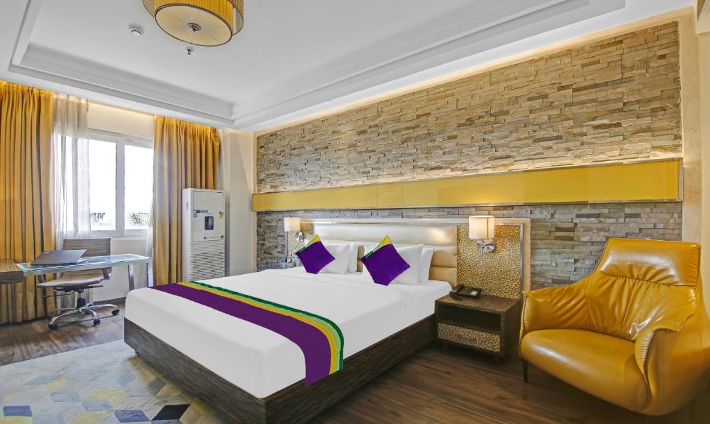 una camera d'albergo con letto e sedia di Treebo Tryst Arista a Chandīgarh
