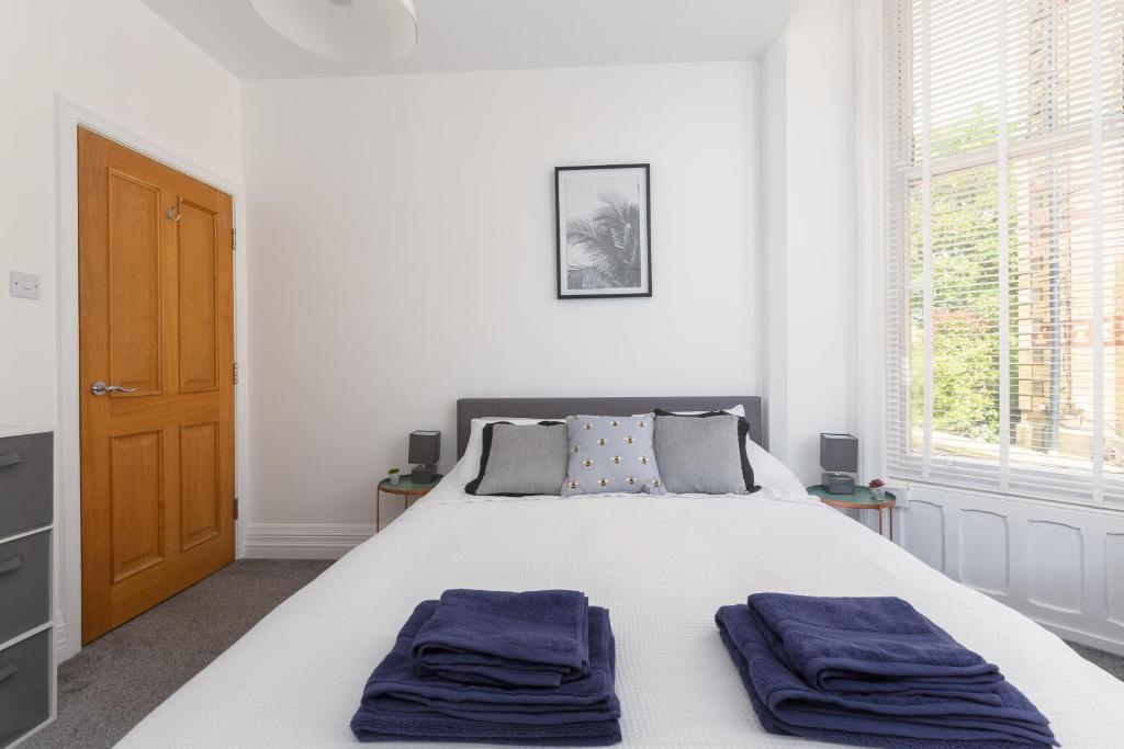 a bedroom with a bed with two blue towels on it at Charles Alexander Short Stay - Clifton Drive Beach Retreat in Saint Annes on the Sea