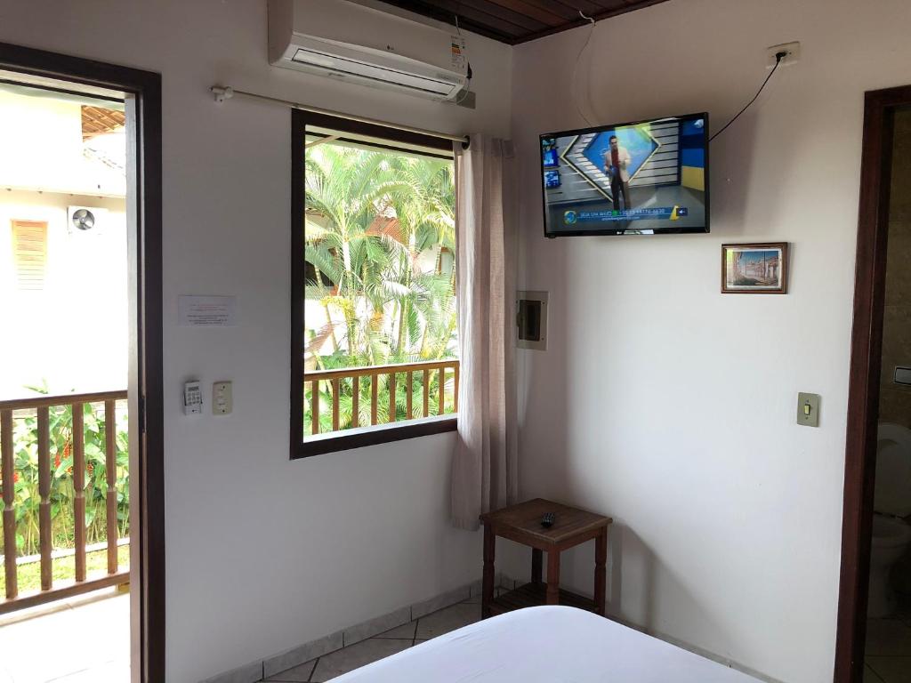 a room with a tv and a bed and a window at Pousada Casa Do Mar in Paraty