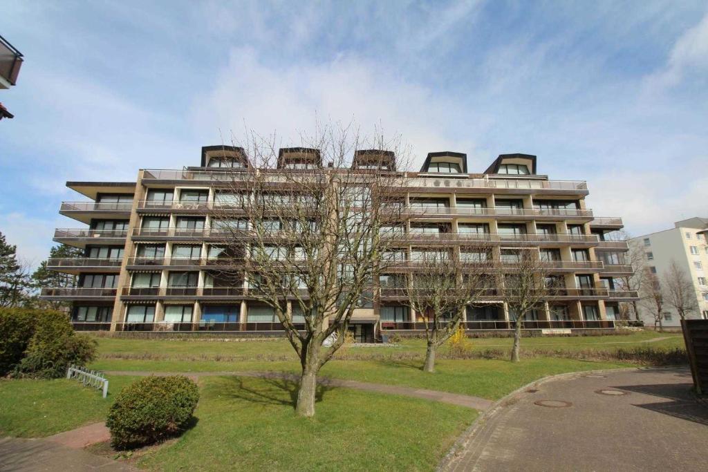 een groot gebouw met een boom ervoor bij Residenz Jan am Strand in Cuxhaven