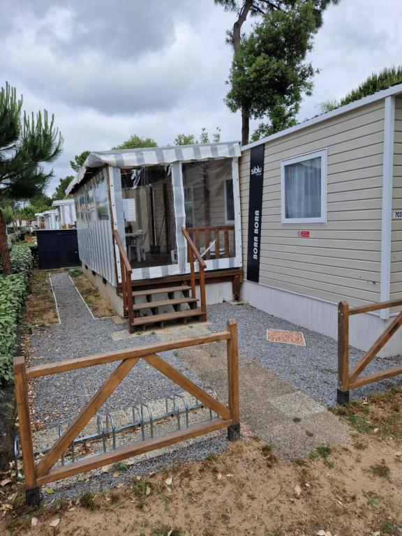 a tiny house with a porch next to a building at spacieux mobil-home 3 ch in Saint-Jean-de-Monts