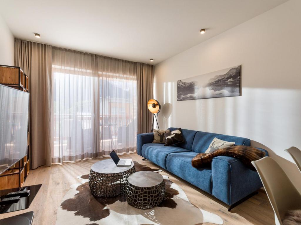 ein Wohnzimmer mit einem blauen Sofa und einem Tisch in der Unterkunft Apartment Liebelei am See - Kaiserblick, nah am Wasser und neuerbaut in Walchsee