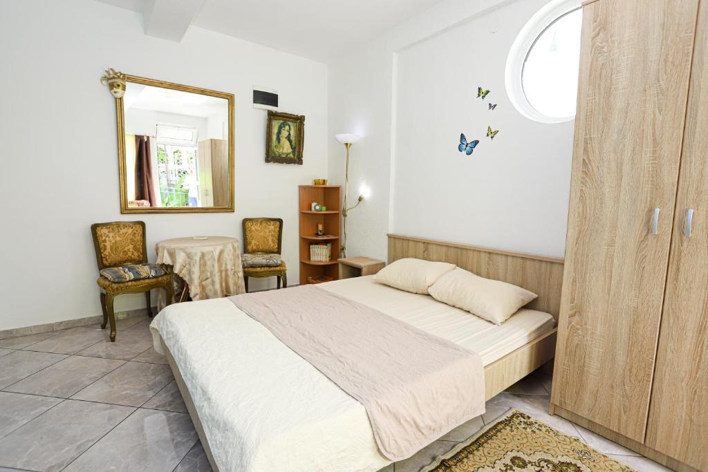 a bedroom with a bed and a mirror and a table at Guest House Topla in Herceg-Novi