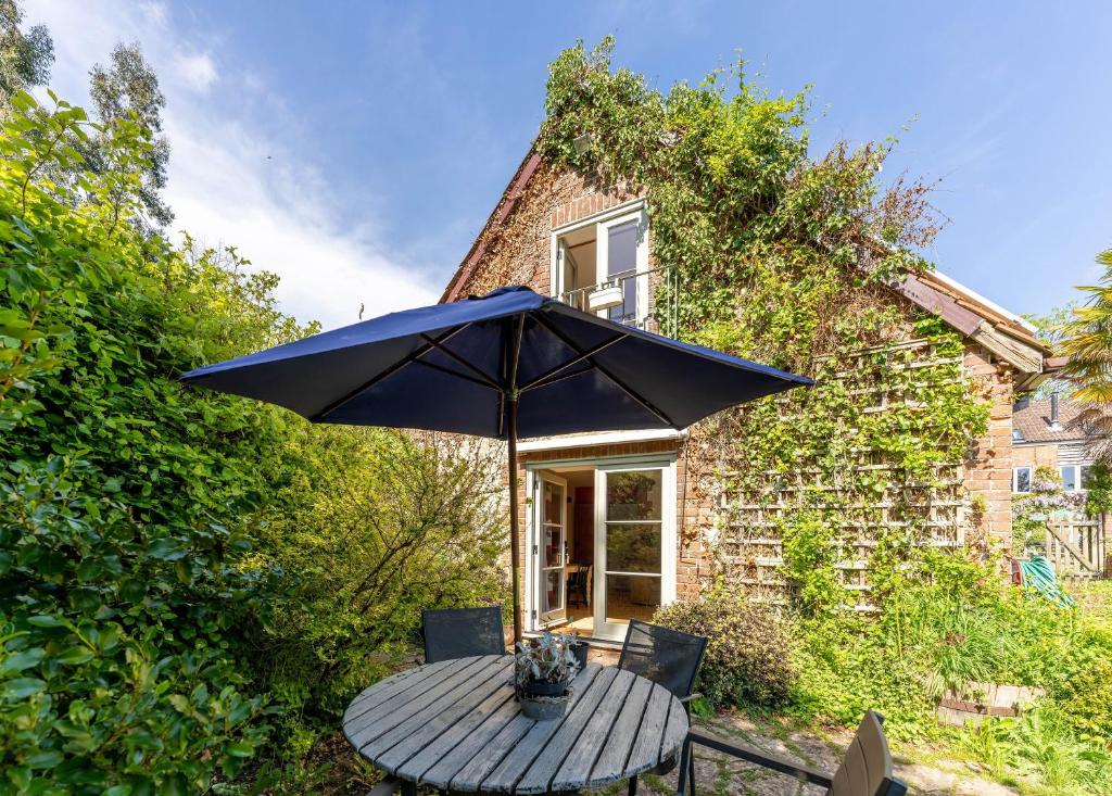 a table with an umbrella in front of a house at Bramley Cottage in Ottery Saint Mary