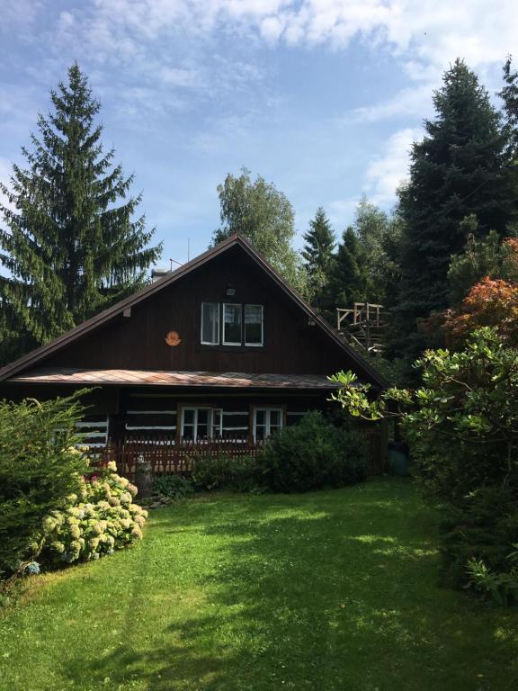 una casa con un patio verde delante de ella en Roubenka Prašivá, en Vyšní Lhoty