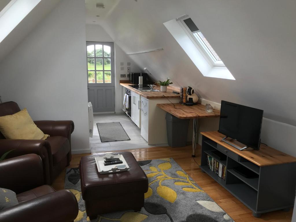 uma sala de estar com um sofá, uma televisão e uma cozinha em The Cartlodge em Hollesley
