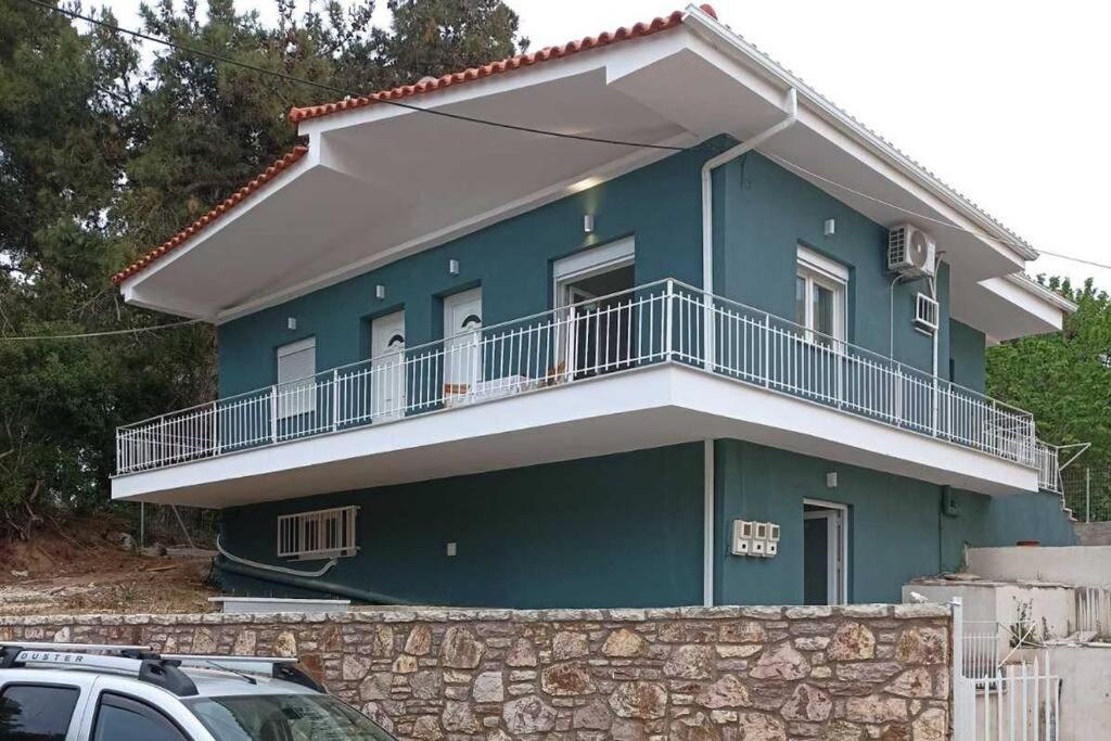 a blue house with a balcony on top of it at Διαμέρισμα κοντά στην θάλασσα in Arkoudi