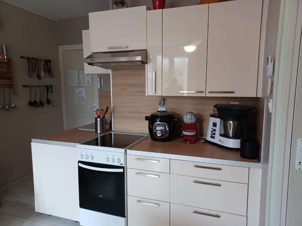 uma cozinha com armários brancos e um forno com placa de fogão em Appartement 3 étoiles - 1 chambre Les Becs em Saint-Hilaire-de-Riez