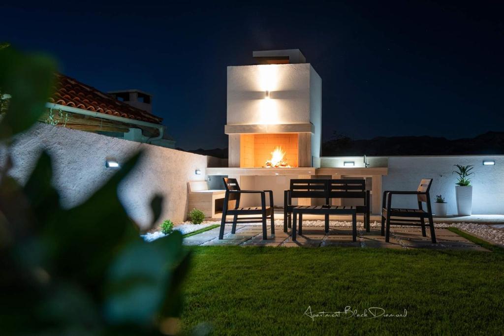 a patio with chairs and a fireplace at night at Apartment Black Diamond in Ražanac