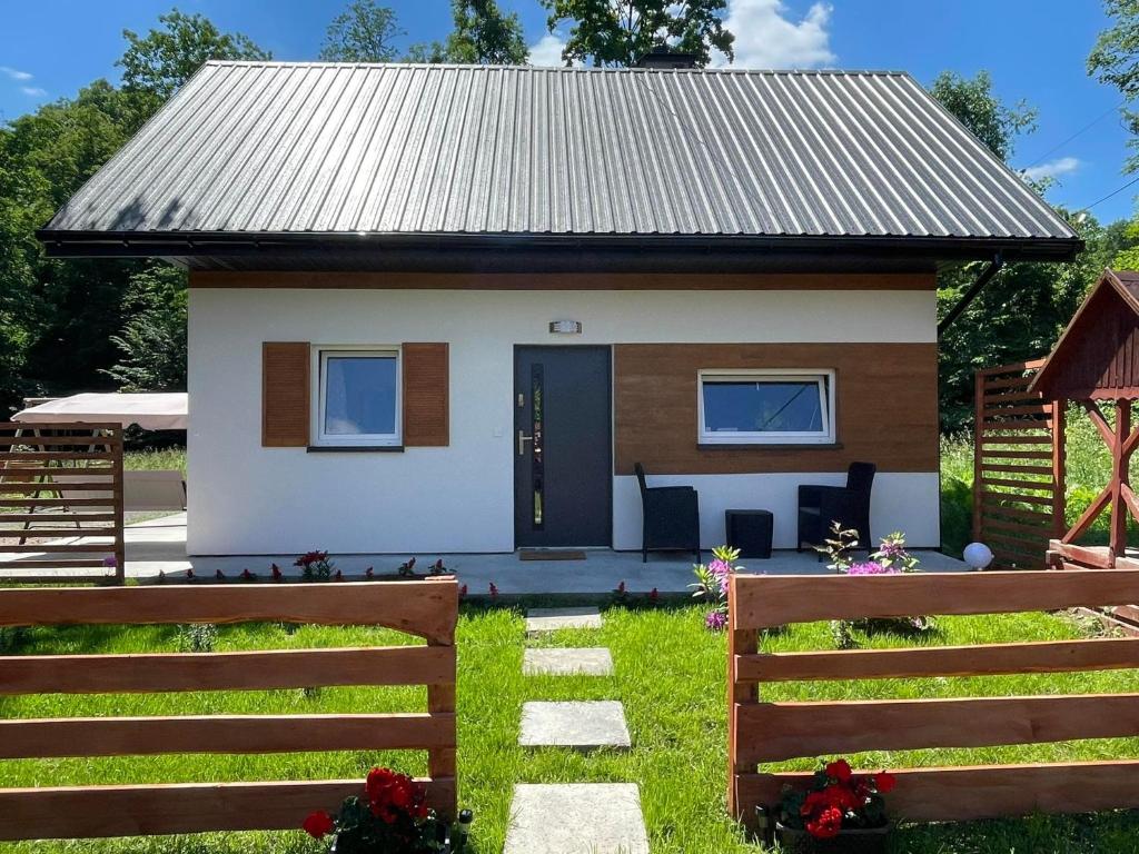 une petite maison blanche avec un toit en métal dans l'établissement Domek całoroczny Zagroda MłyńSKI, à Sułkowice