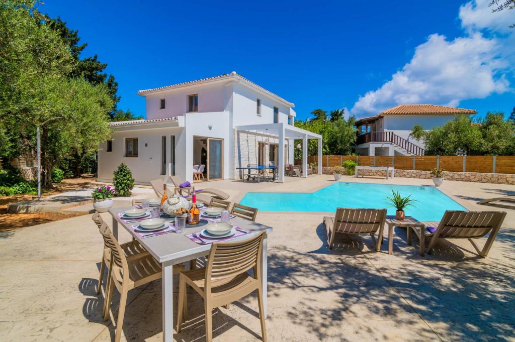 a patio with a table and chairs next to a pool at Villa Ionio Deste by Villa Plus in Vasilikos