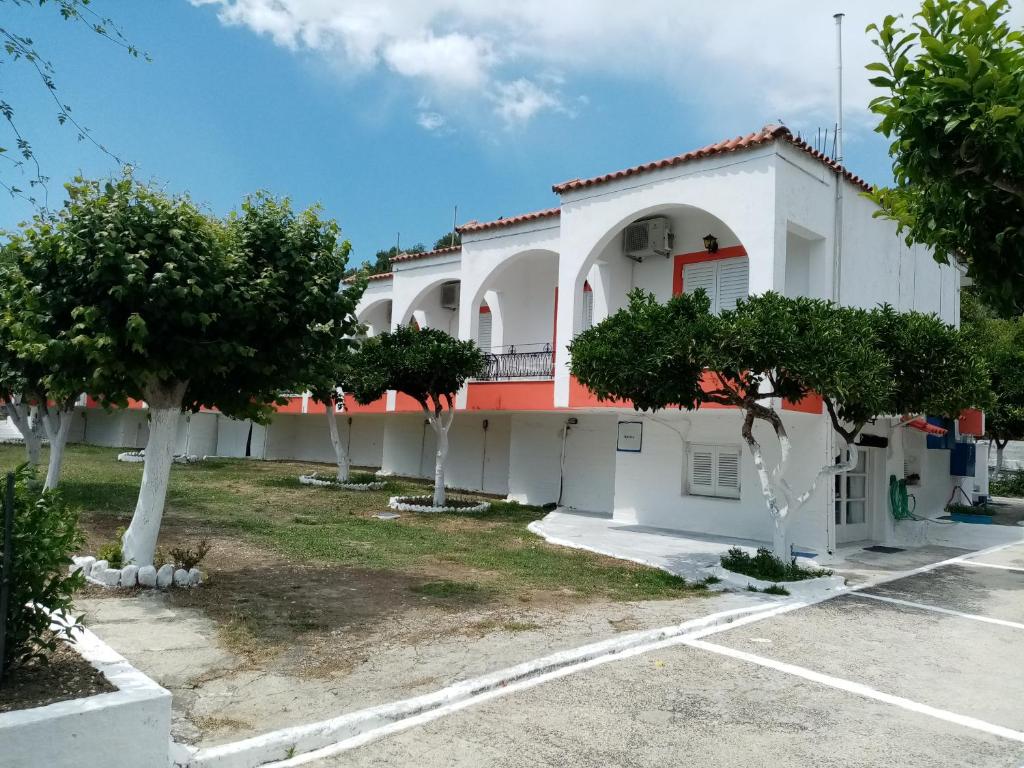 un edificio blanco con árboles en un aparcamiento en Villa Nikitas, en Parga