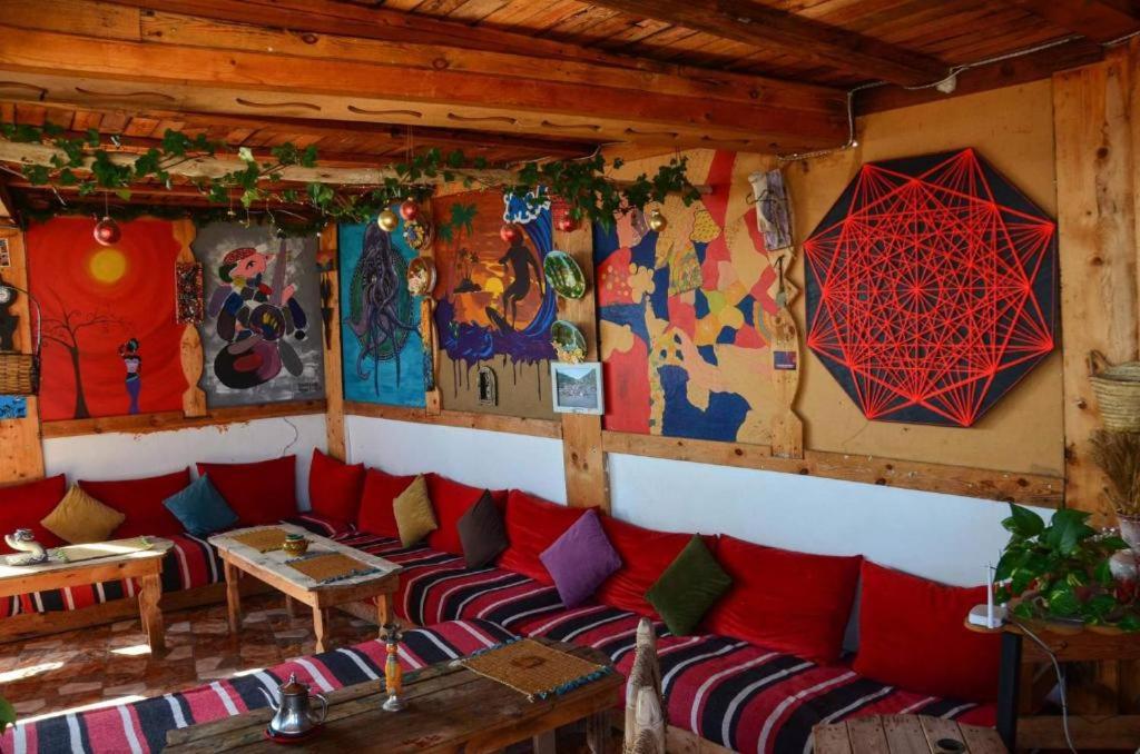 una camera con un divano rosso e quadri alle pareti di Tayought Surf House a Taghazout