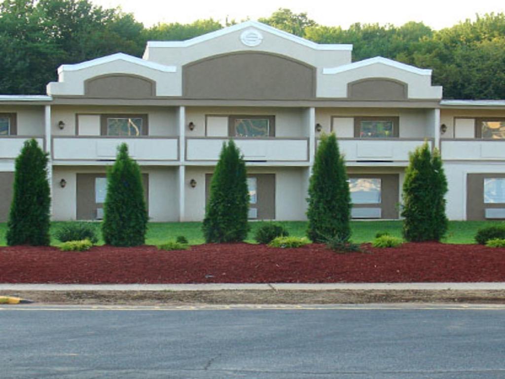 a large white building with trees in front of it at Hotel Vicenza in Monmouth Junction