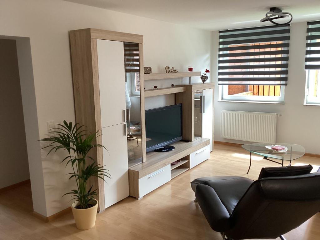 a living room with a television and a black chair at Ferienwohnung Dinkelberg in Steinen