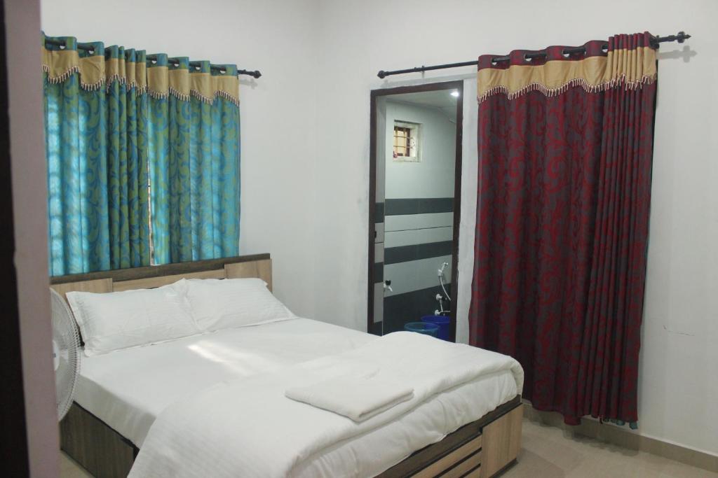 a bedroom with a bed and a red curtain at Wayanad Days in Mananthavady