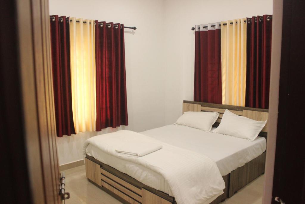 a bedroom with a bed with red curtains at Wayanad Days in Mananthavady