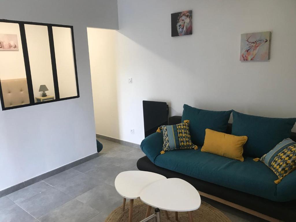 ein Wohnzimmer mit einem blauen Sofa und 2 Tischen in der Unterkunft Superbe studio entièrement refait a neuf in Figeac