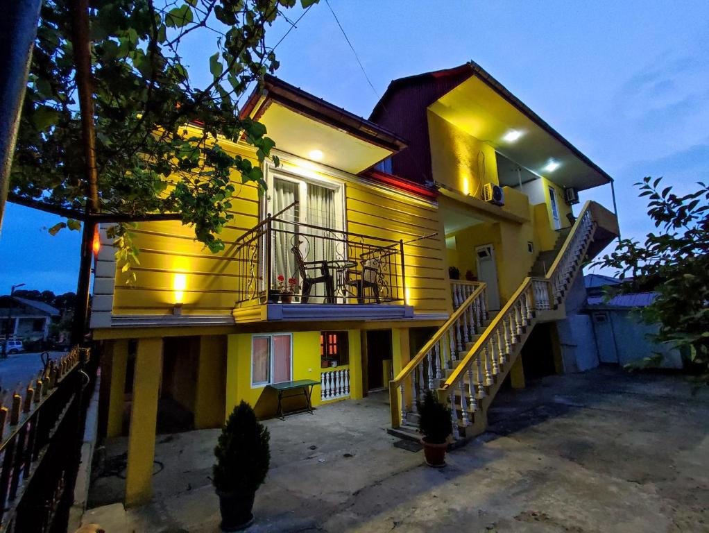 a yellow house with a porch and a balcony at Kobuleti Guest House in K'obulet'i