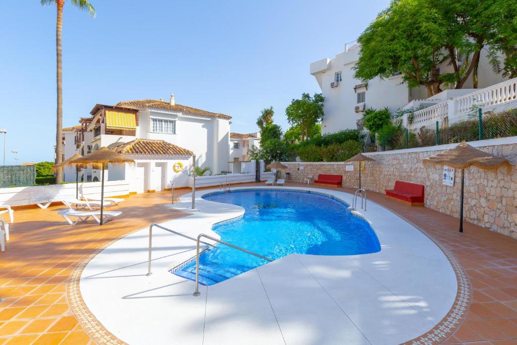 a swimming pool in the middle of a courtyard with a house at Cute apartment oceanfront in Benalmádena