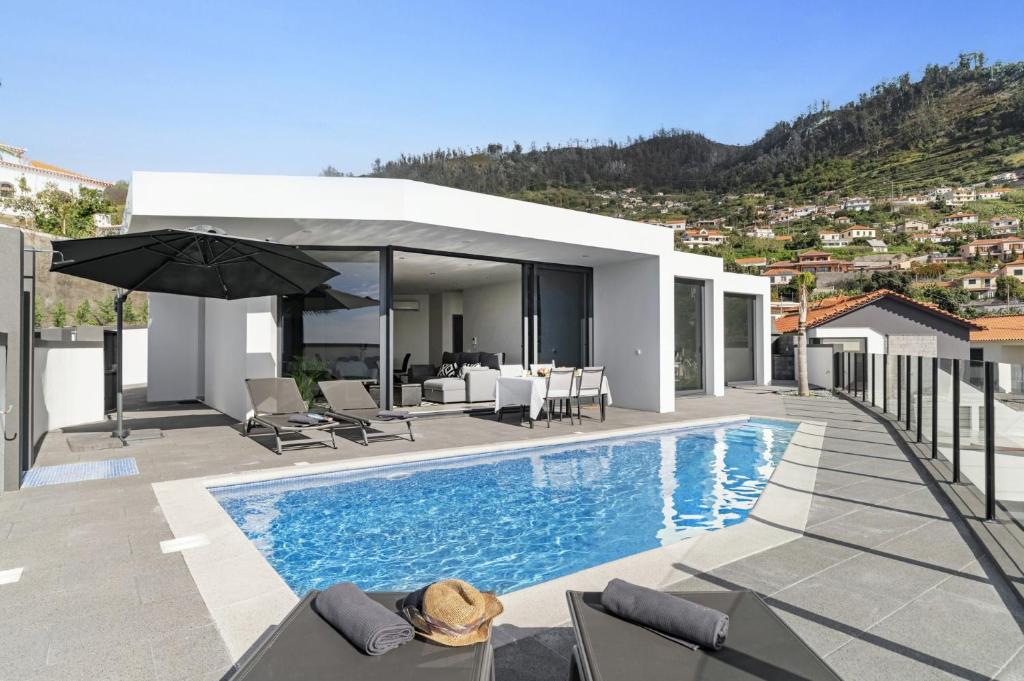 een villa met een zwembad en een huis bij Villa Calheta Charm by Villa Plus in Arco da Calheta