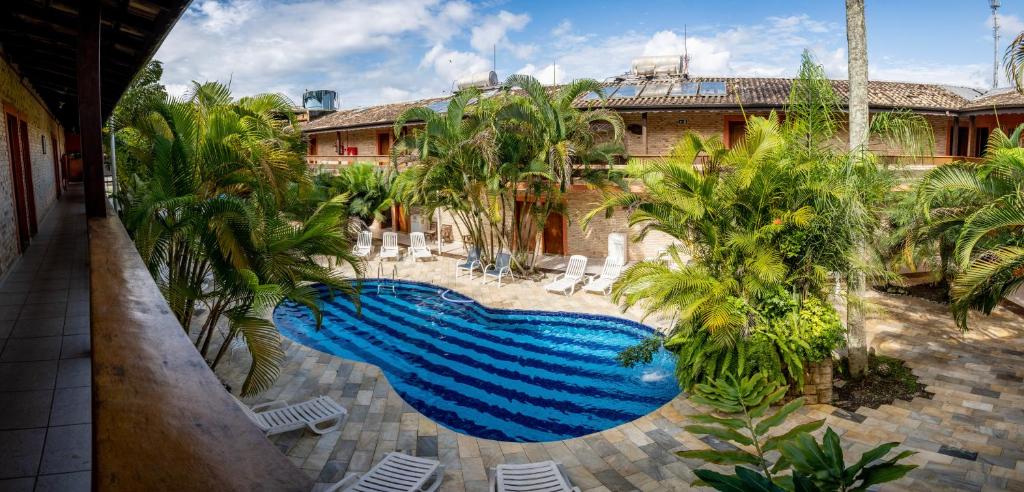 a swimming pool in a courtyard with palm trees at Hotel Dellamares in Ubatuba